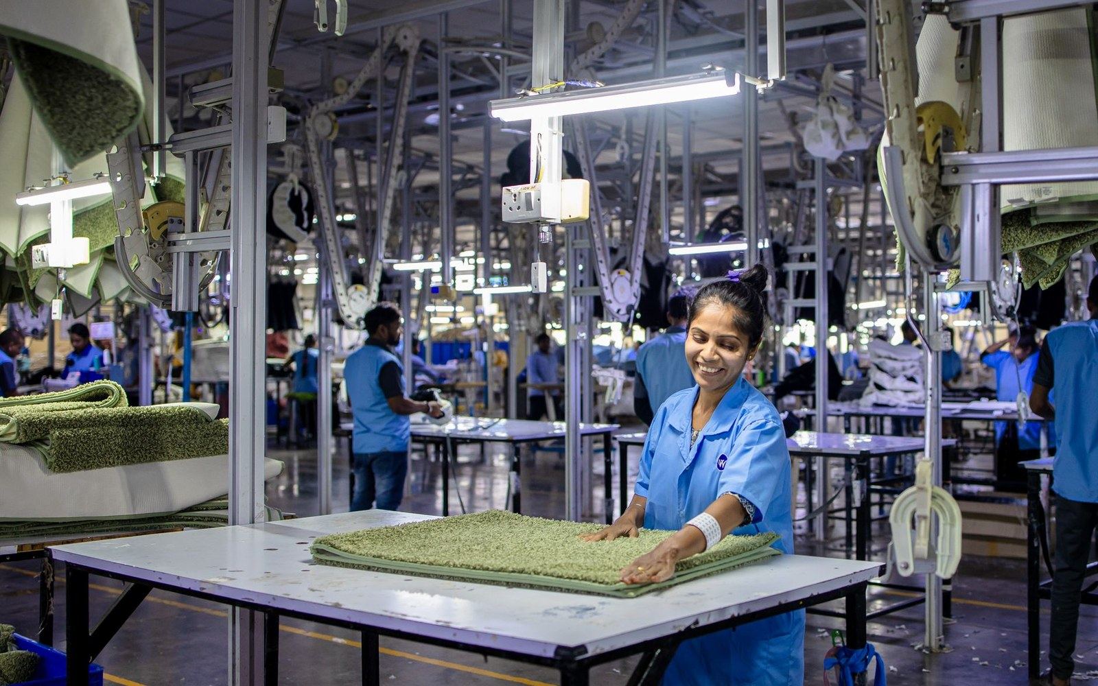 Camera assembly line, adult workers at benches, Pentax bodies at various stages of assembly