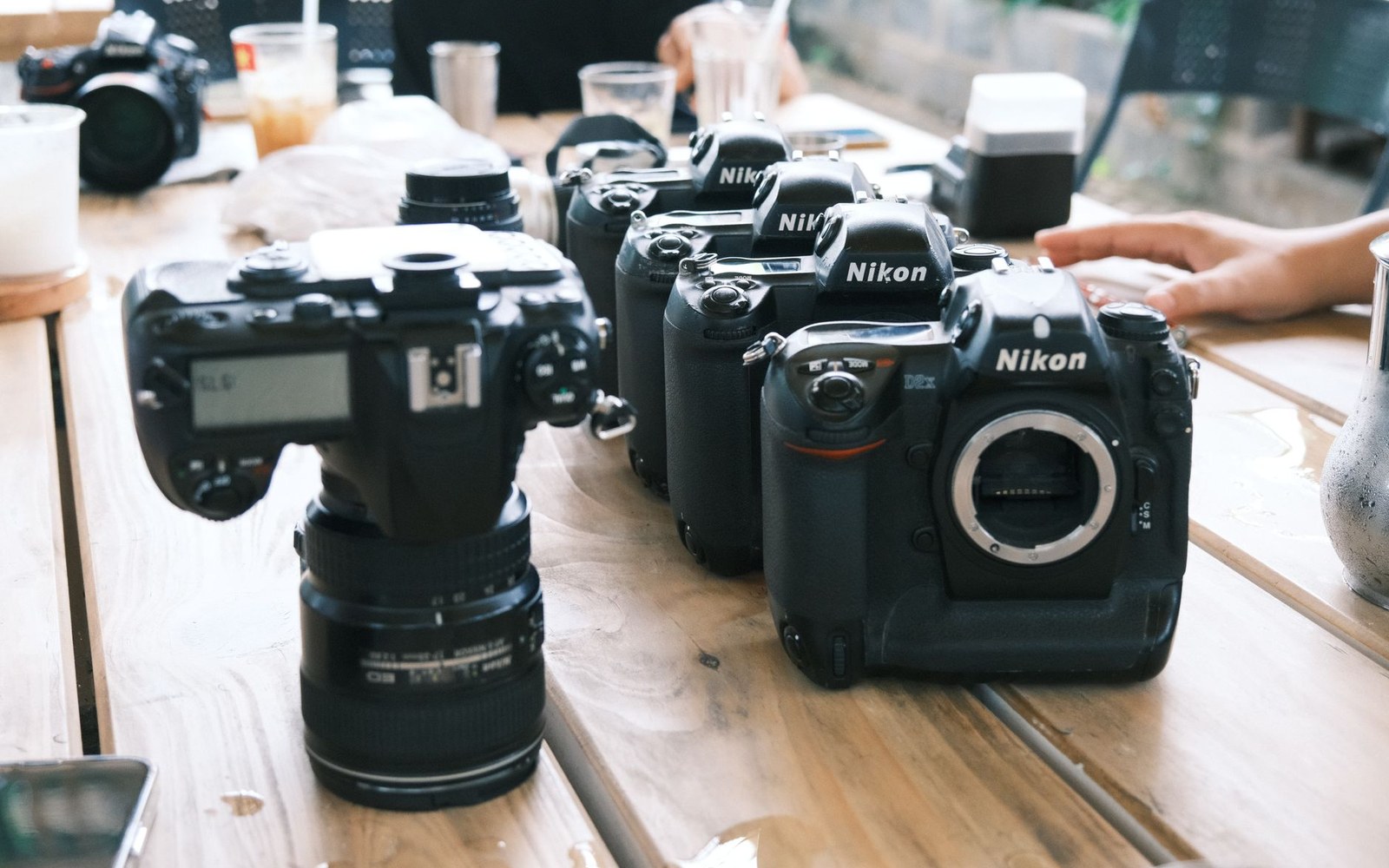 Several Nikon DSLR camera bodies lined up on a wooden table without lenses attached