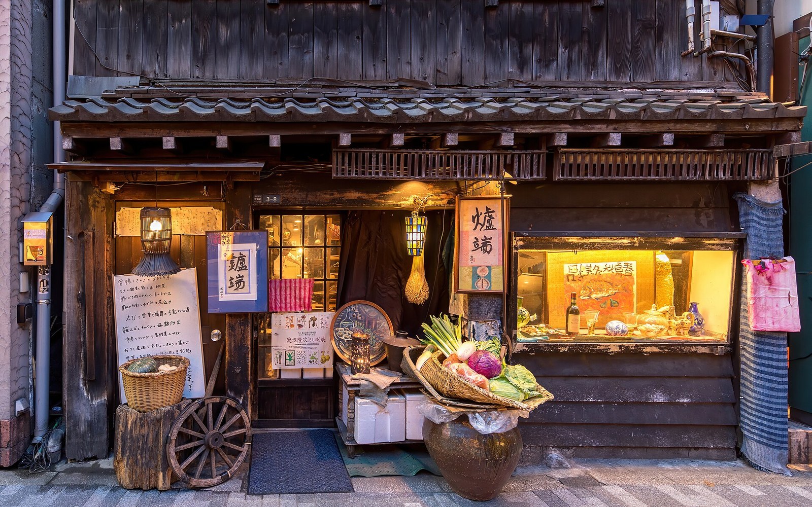 Traditional wooden restaurant facade with lanterns, vegetable baskets and a wagon wheel display