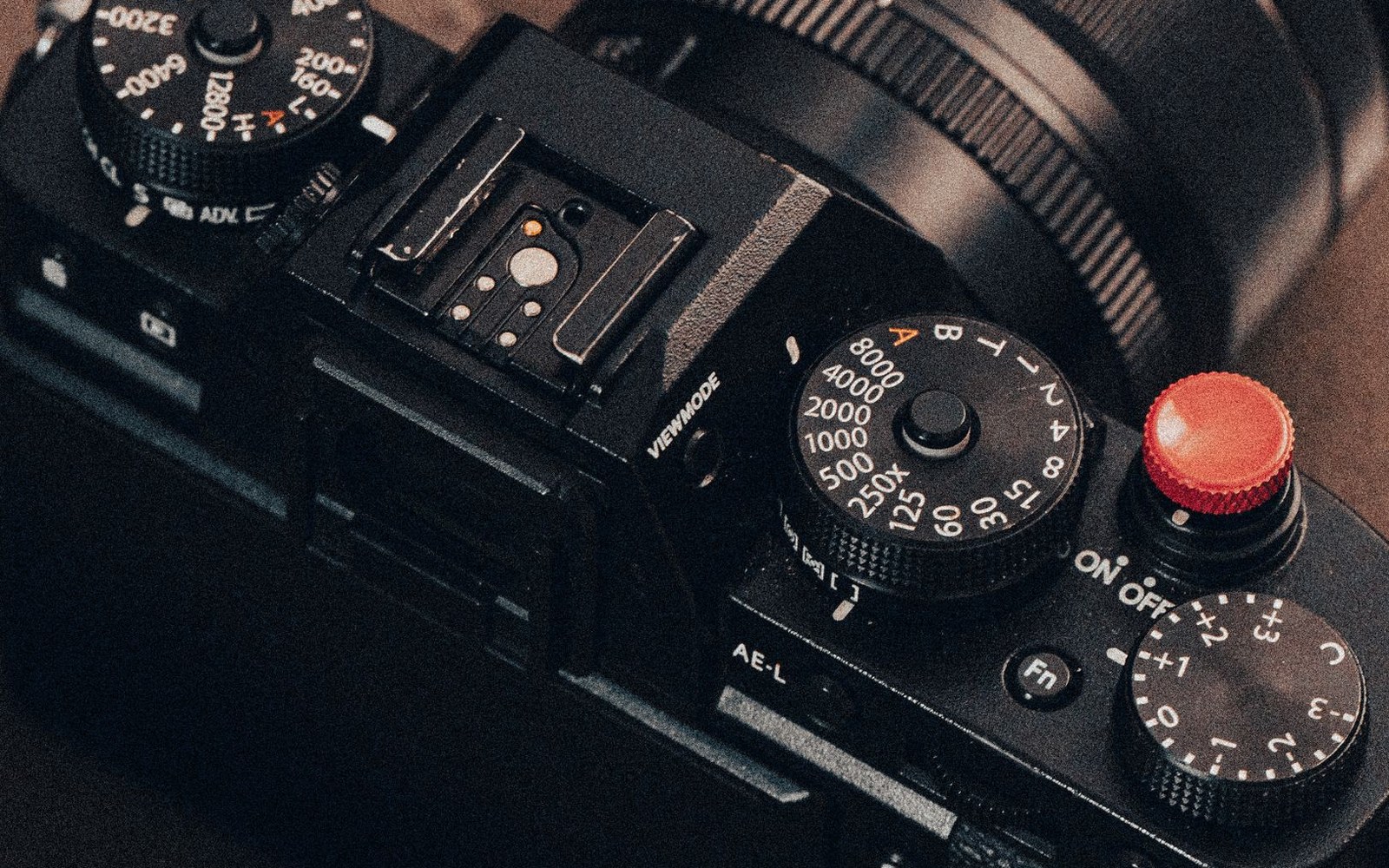 Close-up of a mirrorless camera's top dials, hot shoe, and red shutter button
