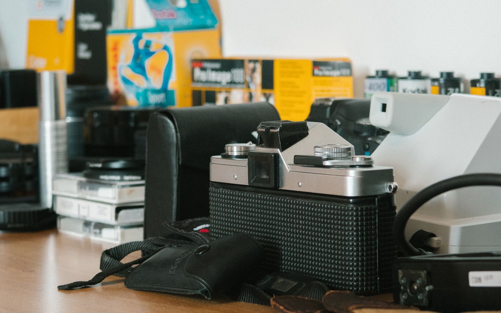 A vintage film camera surrounded by film canisters, boxes and old photo equipment on a desk