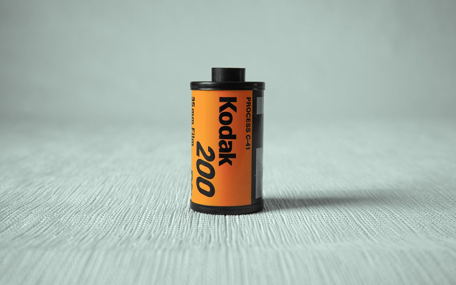 Pentax 17 half-frame body loaded with a 35 mm film canister on a workbench, adult hands threading the leader