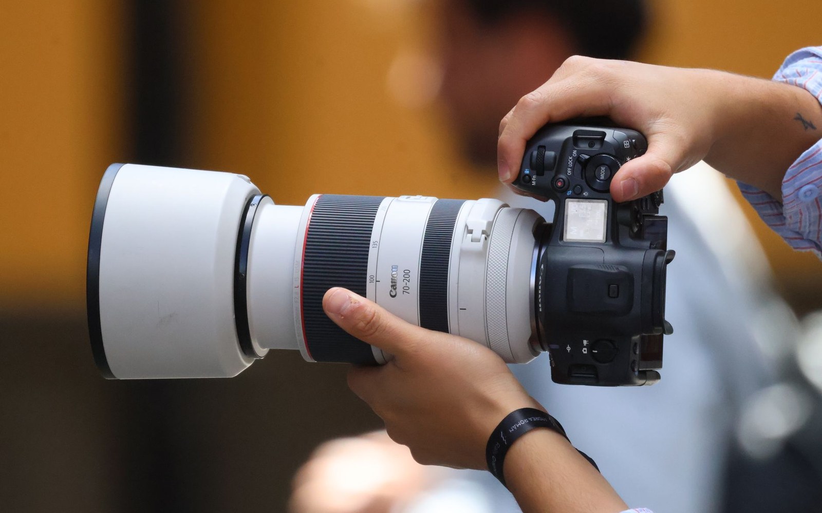 Pentax K-3 III with shutter held open, APS-C sensor plane visible under studio light, adult photographer's hands steadying the body